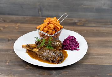 Rehhaxe serviert mit Blaukraut und Süßkartoffelpommes